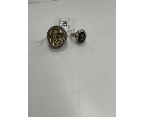 A white metal dress ring with pale citrine stone of large proportions, the shoulders with scrolling foliate design, size R, t