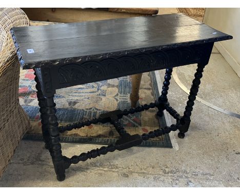 A late Victorian carved oak Gothic Revival side table, the two plank top with foliate carved edge over a foliate lunette carv