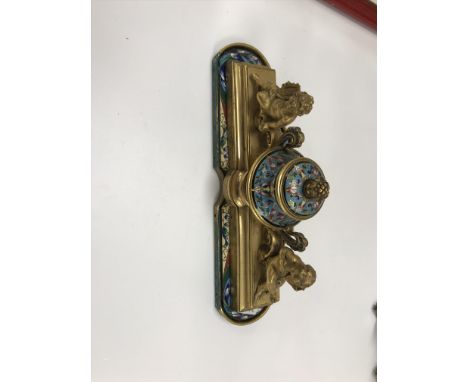 A 19th Century gilt metal and cloisonné inkwell, the central well flanked by two putti, one with lyre, the other with mirror,