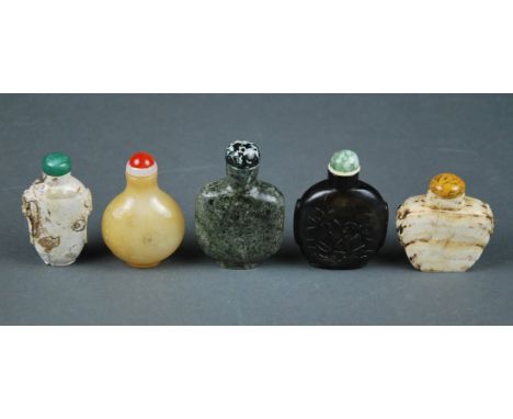 FIVE CHINESE ASSORTED SNUFF BOTTLES Comprising a pear shaped honey toned agate bottle carved with blossoming plum branches, c