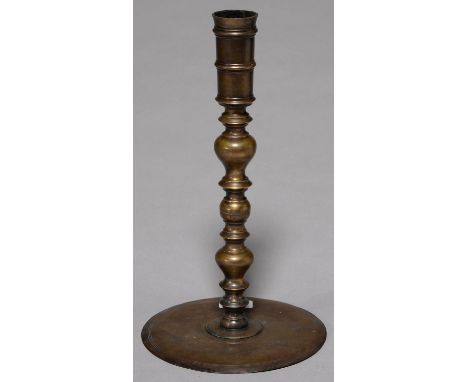 A MIDDLE EASTERN BRASS CANDLESTICK, 19TH C, THE BANDED SCONCE ON MULTI KNOP STEM AND ALMOST FLAT BASE WITH TURNED LINES, 35CM