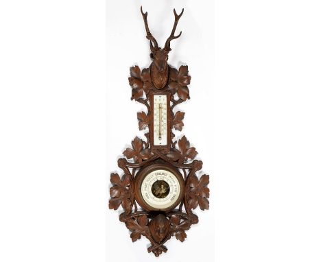A SWISS CARVED LIMEWOOD ANEROID BAROMETER, EARLY 20TH C, WITH THERMOMETER, CARVED IN FULL RELIEF WITH THE HEADS OF A DEER WIT