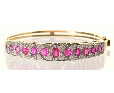 A RUBY AND DIAMOND BANGLE, LATE 20TH C, THE LINE OF LARGER GRADUATED RUBIES CENTRING A DIAMOND TRELLIS, MILLEGRAIN SET IN GOL