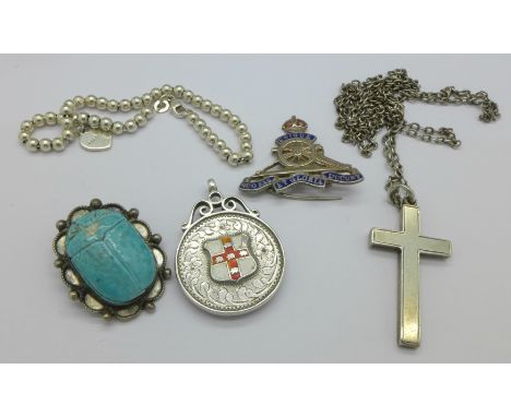 A silver Royal Artillery badge, a silver and enamel medallion, a silver cross pendant, a scarab brooch and a silver bracelet