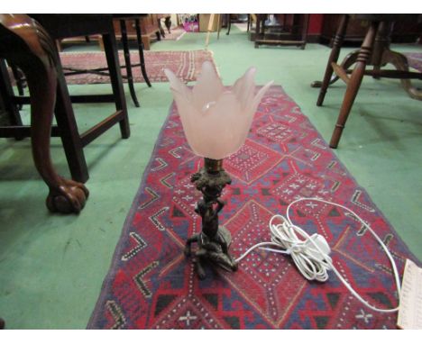 An ornate bronzed table lamp in the form of a putti seated on alligator under branching grapevines with pink frilled shade, 3