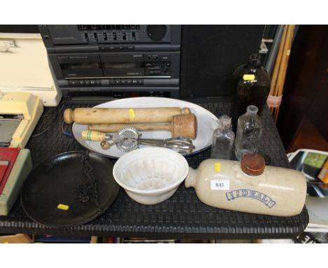 An enamelled cooking dish; various glass bottles; a rolling pin; hot water bottle; jelly mould 