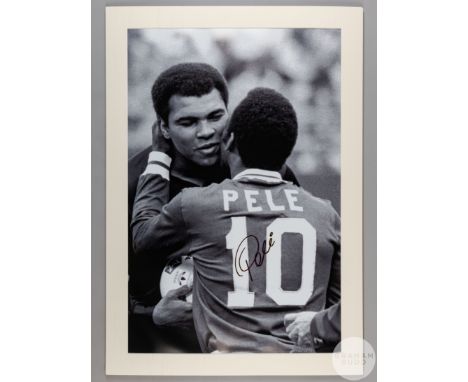 A large black and white photographic print of Pele embracing Muhammad Ali,&nbsp;
signed on the front by Pele in black pen,&nb