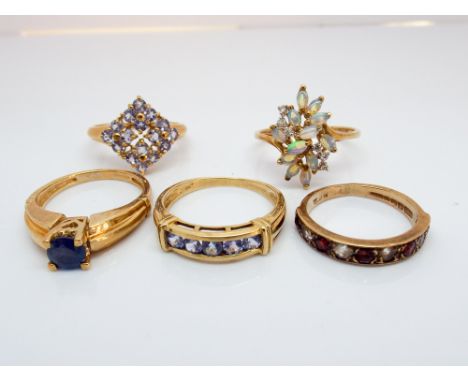 Five modern 9ct yellow gold gem set ladies dress rings to include opal and tanzanite, various sizes N-Q