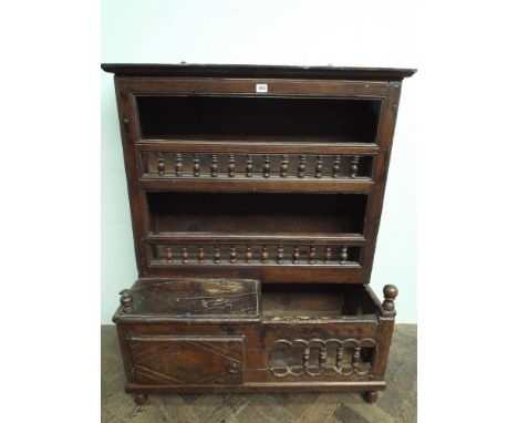 An antique carved oak kitchen plate rack with small cupboard to the base and bobbin turned lined shelves, height 110cms high 