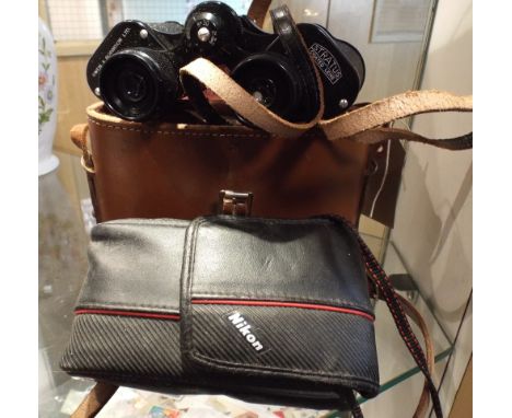 An old Nikon camera and a set of binoculars in a faux leather case 