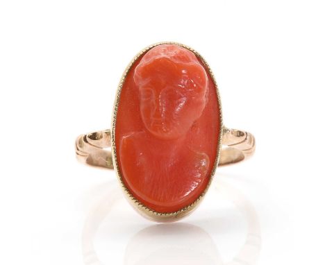 A Continental carved coral cameo ring,  depicting a lady in profile, milligrain set to a plain collet with ridged shoulders, 