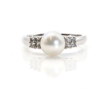 A single stone cultured pearl ring with diamond set shoulders,  with a 7.50mm cultured pearl peg set to the head. Four brilli