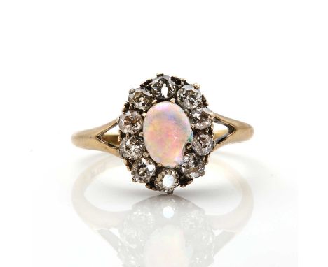 An opal and diamond oval cluster ring, an oval cabochon opal, chipped, claw set to a surround of old European cut diamonds, a