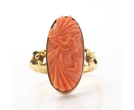 A Continental carved coral cameo ring, depicting a lady in profile, rub set to a plain collet with split shoulders with flowe