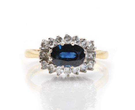 An 18ct gold sapphire and diamond cluster ring, an oval mixed cut sapphire, approximately 5.40mm x 8.00mm, claw set to the ce