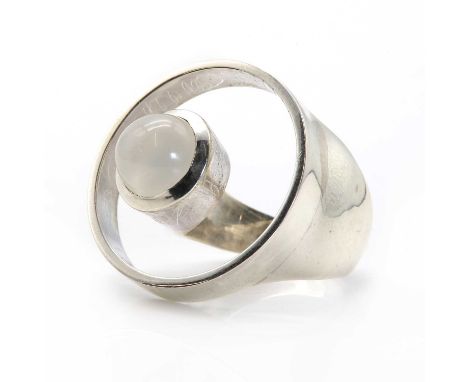 A silver moonstone abstract design ring, the circular openwork ring head, with a round cabochon moonstone rub set to the floa