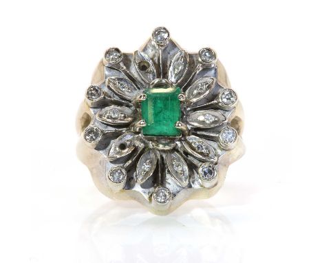 An emerald and diamond cluster ring, with an emerald cut emerald, four claw set to the centre of a border of petals, grain se