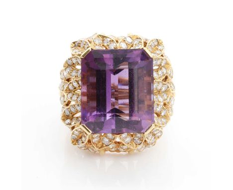 A large amethyst and diamond ring, the emerald cut amethyst four claw set above a pierced cascade of diamond set leaf motifs,