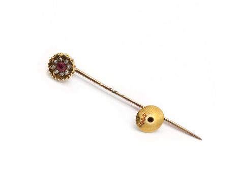 A gold ruby and diamond tie pin,a round mixed cut ruby bead set to the centre of the circular piece, to a surround of old eig