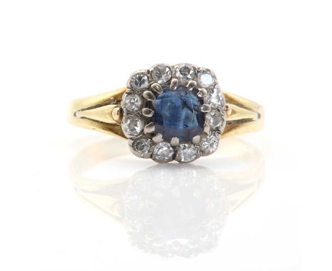 A gold sapphire and diamond cluster ring, a cushion mixed cut sapphire claw set to a surround of eight cut diamonds, all bead