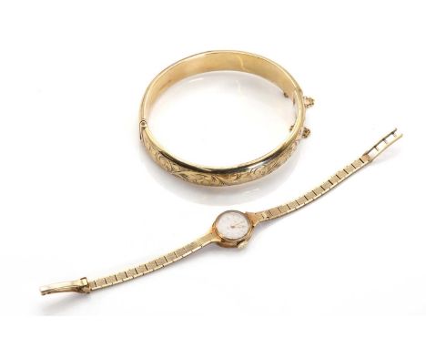 A 9ct gold hinged bangle,the hinged hollow D section bangle with scrolling foliate decoration to the front, snap catch and sa