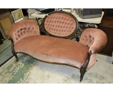 A Victorian sofa, deep button oval back, scrolling arms, carved forelegs.