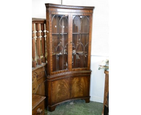 A Regency reproduction walnut veneered inverted bow front floor standing corner cupboard, stepped cornice, dentil frieze, two