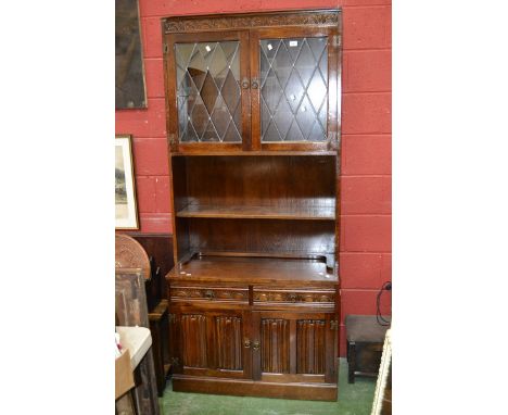 A Priory style bookcase cupboard, lead glazed two door cupboard and shelf to top, two short drawers over two linenfold door c