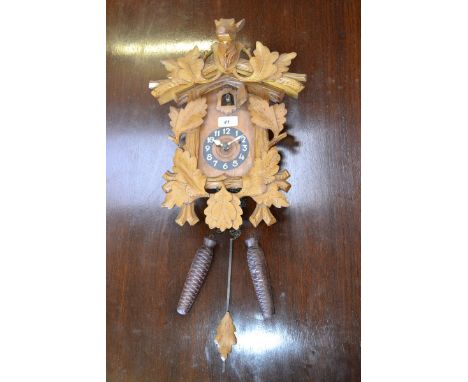A cased wooden cuckoo clock with weights and pendulum