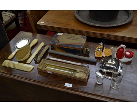 An early 20th century Lyon's biscuit tin containing a cake icing set; an ivorine dressing table set; a floating dairy thermom