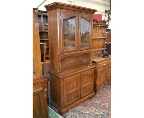 A 20th century mahogany dresser of narrow proportions, moulded pediment, a pair of glazed doors enclosing a single shelf, a p