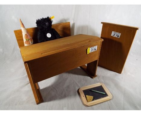 A Steiff black bear (Teddybar 1912) Button in ear, yellow tag # 029257, 18 cm (h) seated in a miniature school desk with teac