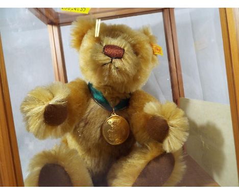 Steiff bear - a glazed display case containing the 2001 Steiff bear issued in a limited edition, with button in ear, yellow t