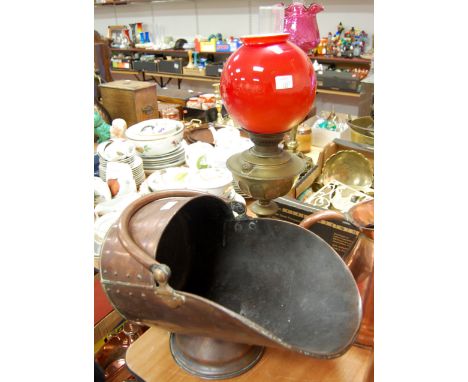 An early 20th century brass pedestal oil lamp with red globular shade, together with a copper coal scuttle (2) 