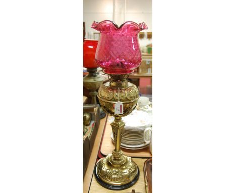 A Victorian Hinks No.2 embossed brass pedestal oil lamp, with later cranberry glass shade 