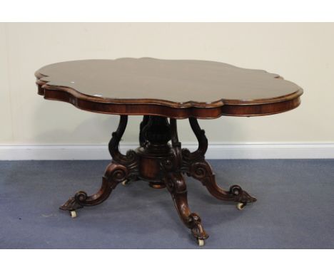 An early Victorian rosewood tip-top breakfast table, the shaped top above a central carved baluster stem and four scrolling d