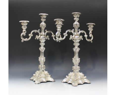 A pair of Continental plated twin scroll branch three light candelabra with detachable nozzles, each on a baluster stem and s
