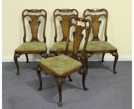 A set of four early 20th Century Queen Anne style walnut dining chairs with carved vase backs and floral tapestry drop-in sea