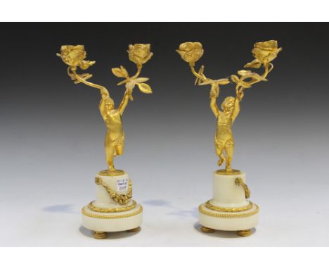 A pair of early 20th Century French cast ormolu and white marble candelabra, each putto stem supporting two floral sconces, r