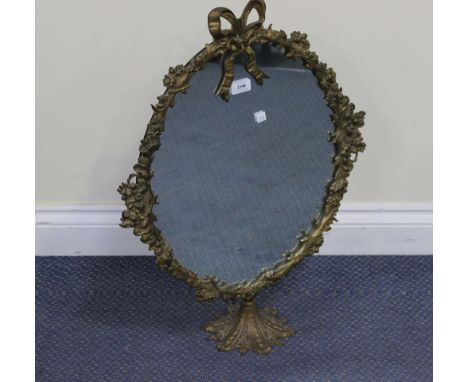 An early 20th Century gilt metal dressing table mirror, the oval frame cast with flowers and a ribbon surmount, raised on a s