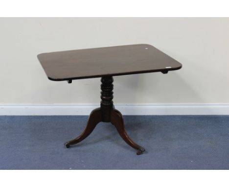 An early Victorian mahogany tip-top wine table, the rectangular top above a turned column, on tripod cabriole legs with brass