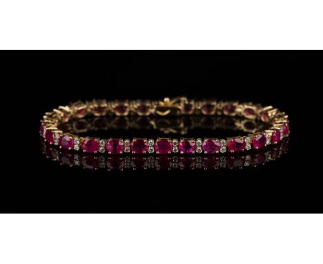 An 18ct gold, ruby and diamond bracelet, claw set with a row of oval cut rubies alternating with pairs of circular cut diamon