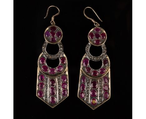 A pair of ruby and diamond pendant earrings, each in a pierced circular and panel shaped design, mounted with oval cut rubies