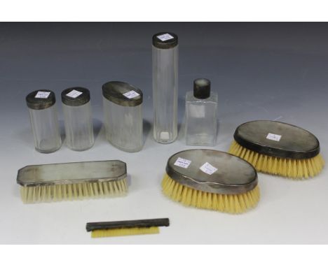 A group of silver and clear glass dressing table bottles and jars, each silver cover with engine turned decoration, London 19