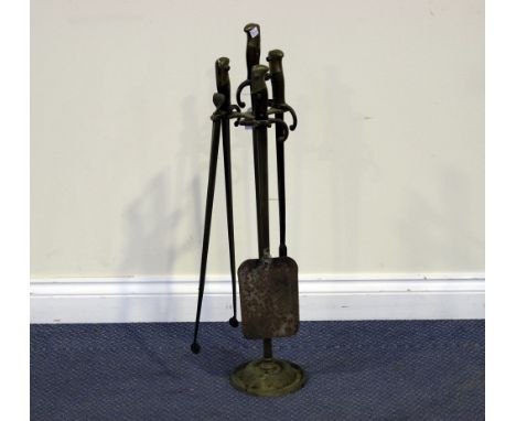 A set of three brass fire tools, formed from military bayonets, supported on a stand with bayonet handle finial, height appro