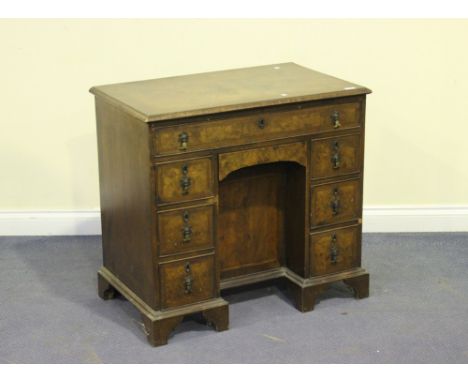 An early 20th Century George I style walnut kneehole desk, fitted with an arrangement of eight drawers and a cupboard, on sha