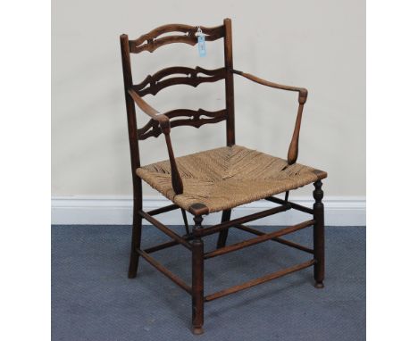 A late 19th Century Arts and Crafts ash pierced ladder back armchair, the woven string seat flanked by shaped arms, on turned