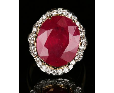 An 18ct gold, ruby and diamond ring, claw set with a large oval cut ruby within a surround of circular cut diamonds, detailed