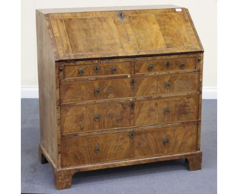 An early 18th Century figured walnut bureau with feather and crossbanded decoration, the fall front revealing a fitted interi