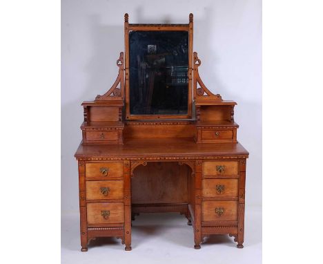 In the manner of Charles Bevan - an Arts &amp; Crafts oak and inlaid kneehole dressing table, having swing mirror back, raise